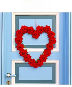 Detail of red rose heart wreath hanging on a blue door with a silk ribbon for decoration