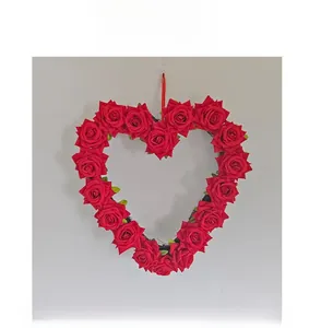 Front view of heart-shaped red silk rose wreath with a hanging ribbon on white wall