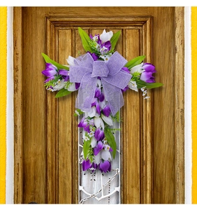 Detail van tulpenkruiskrans met paarse strik op een rustieke houten deur decor