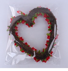 Detail of a heart-shaped rattan wreath with red roses and green leaves in packaging