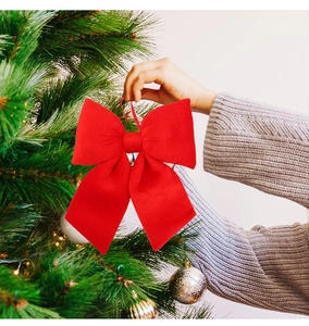 Close-up of a large red velvet bow being placed on a decorated Christmas tree branch
