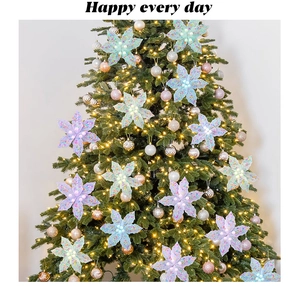 Gros plan de fleurs de Noël pailletées aux couleurs macaron sur un sapin décoré
