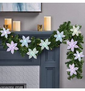Gros plan de fleurs de poinsettia artificielles pailletées sur guirlande de cheminée