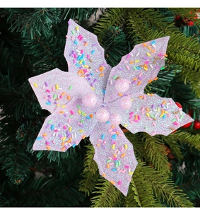 Gros plan d'une fleur de Noël rose pailletée avec des confettis sur un sapin vert