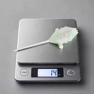 Weight measurement of a macaron glitter leaf ornament on a scale at 14 grams