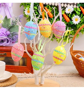 Seis huevos de Pascua coloridos con purpurina colgados de una rama decorativa blanca