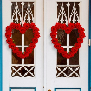 Set of 2 artificial red rose heart wreaths hanging on a vintage white wooden door
