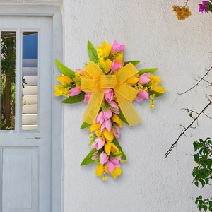 Kruisvormige paaskrans met roze en gele tulpen, groene bladeren en een grote strik