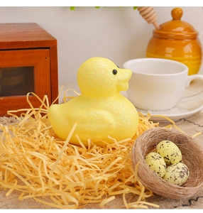 Detail of yellow glitter duck figurine with speckled eggs in a spring bird nest decor