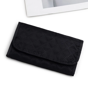 Portable black faux suede jewelry roll with quilted diamond pattern and flap closure