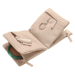 Macro detail of apricot velvet jewelry roll showing multiple zippered storage compartments