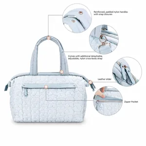 Detail of light blue quilted diaper bag showing padded handles and detachable shoulder strap