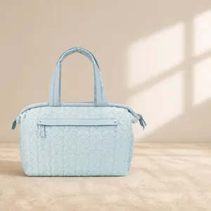 Quilted light blue diaper bag with floral embroidery and spacious front zipper pocket