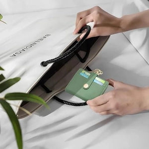Sage green RFID leather card holder with gold clasp and hook, shown in a lifestyle setting