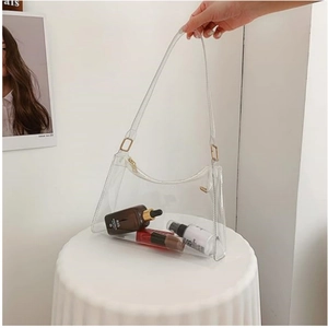 Transparent PVC crescent shoulder bag with white trim and golden hardware detailing