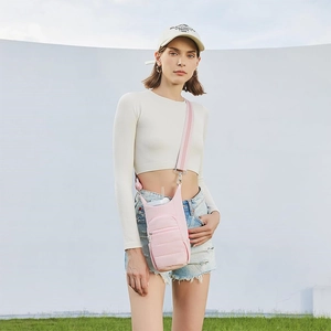 Pink nylon crossbody water bottle bag with adjustable strap worn by model outdoors