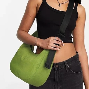 Green hobo shoulder bag with adjustable black strap shown on a model for scale