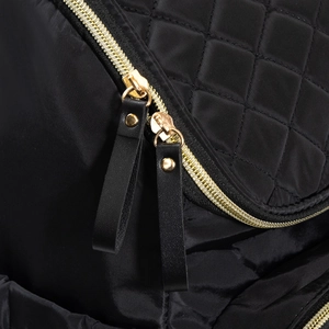 Gros plan sur les fermetures éclair dorées et le tissu matelassé noir du sac à langer design