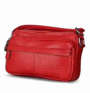 Detail view of red pebbled leather crossbody bag with multiple zippers and flap pocket