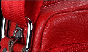 Detail of red lychee grain leather crossbody bag with silver buckle and nylon strap