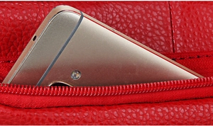 Detailed view of red lychee grain leather crossbody bag with a zipper pocket for a phone