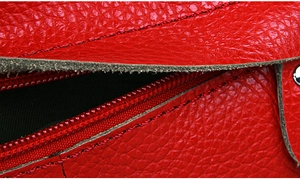 Macro detail of red lychee grain leather crossbody bag with black stitching craftsmanship