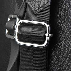 Détail du cuir grainé et de la boucle en métal argenté sur le sac à dos noir
