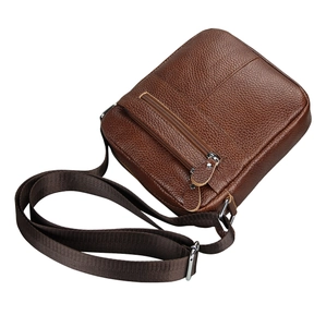 Detail of genuine brown leather messenger bag with grain texture and metallic zippers