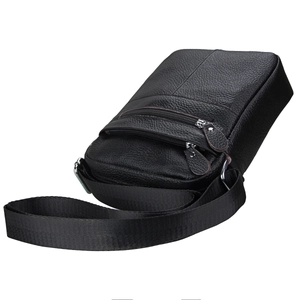 Close-up of black pebble grain leather texture and metallic zippers on crossbody bag