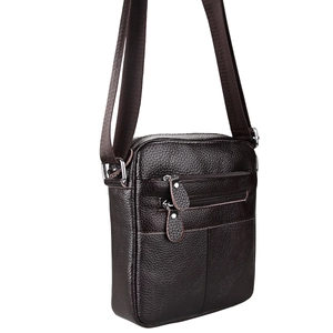 Detail of dark brown pebble grain leather crossbody bag with two front zipper pockets