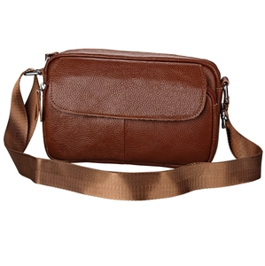 Detail of dark brown pebble grain leather crossbody bag with silver hardware and nylon strap