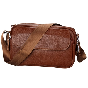 Macro view of brown pebbled leather shoulder bag with zipper detail and silver hardware