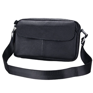 Close-up of litchi grain genuine leather texture and stitching on black crossbody bag