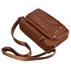 Detailed view of brown leather crossbody bag featuring lychee texture and zipper pockets