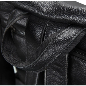 Detail of the top handle and fine stitching on a black pebbled leather backpack