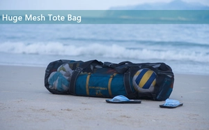 Geräumige schwarze Netztasche am Strand gefüllt mit Volleyball und Schnorchelausrüstung