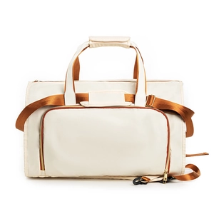 Detail of water-resistant cream fabric travel garment bag with brown straps and gold zippers
