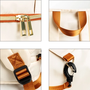 Detailed view of beige travel bag with orange straps, gold zippers and plastic buckles