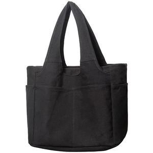Close-up of a black canvas tote bag showing functional outer pockets and durable stitching