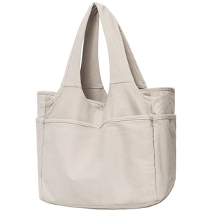 Detail view of beige canvas tote bag showing multiple functional exterior pockets for storage