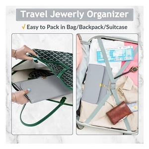 Foldable grey travel jewelry organizer with tassel and gold buckle in a tote bag