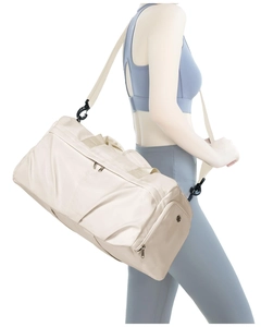 Detail view of cream waterproof fitness bag with shoe compartment and adjustable strap