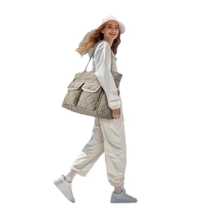 Quilted nylon large tote bag with dual front pockets shown on shoulder in a side view