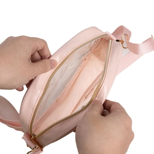 Detail view of the spacious inner compartment and adjustable strap on pink crossbody bag