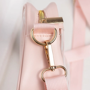 Macro detail of pink leather crossbody bag with gold D-ring and lobster clasp hardware
