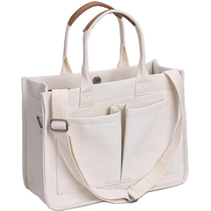 Detail view of large canvas tote bag showing side structure and brown leather handles