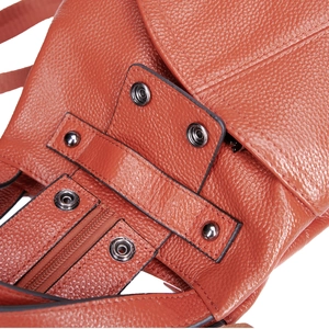 Close-up of orange pebble grain leather backpack with silver metal buckle and stitching