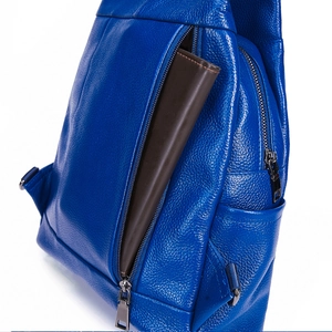 Detail of blue lychee grain leather backpack showing a functional side zipper pocket