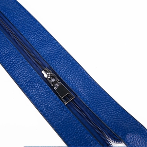 Close-up of a silver zipper on blue litchi-grain leather of a cowhide backpack