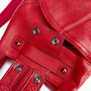 Macro detail of red lychee grain leather backpack with silver metal buckle and stitching
